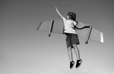 Çocukların lideri ve kazananı, başarı başlar. Çocuk pilot mavi gökyüzüne karşı uçuyor. Heyecanlı çocuk, parkta oyuncak jetpack kanatlarıyla oynuyor.