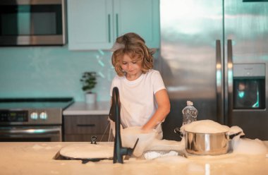 Çocuk bulaşıkları süngerle yıkıyor. Temizlik malzemeleri. Temizliğe yardım et. Oda servisi görevleri. Çocuk bulaşıkları yıkıyor. Küçük hizmetçi. Çocuk mutfakta bulaşıkları yıkıyor ve siliyor.