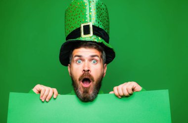 Green patricks background. Man in Saint Patricks Day leprechaun party hat having fun on green background. Copy space clipart