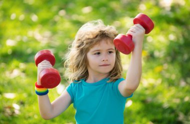 Çocuklar sabah sporu egzersizleri. Çocuklar spor yapar. Dışarıda çocuklarla boş zamanlarında spor faaliyetleri. Güzel sarışın çocuk parkta dambıllar tutuyor.