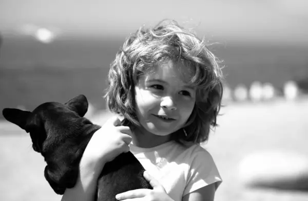 Happy child and puppy dog hugs her with tenderness smiling