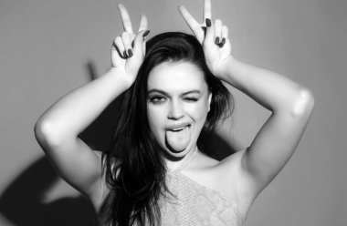 Kadın boynuz gibi parmaklarıyla komik jestler yapıyor. Çılgın komik seksi kız boynuzları gibi parmaklarıyla komik jestler yapıyor. Boynuzlarını gösteren kadın