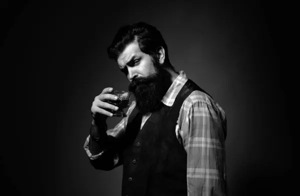 Bartender leather apron holding whisky cocktail in glass. Bearded and glass of whiskey