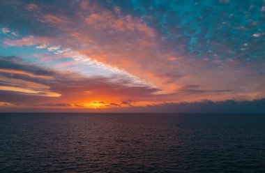 Denizde gün batımı güzel bulutlarla. Güneş doğarken okyanus manzarası