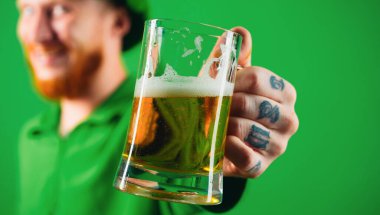 Portrait of excited man holding glass of beer on St Patricks day isolated on green clipart