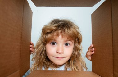 Karton kutulu mutlu çocuk, internet mağazasından paketleri açıyor. Çocuk müşteriler hızlı teslimat hizmetinden memnun. Paketler ve teslimat