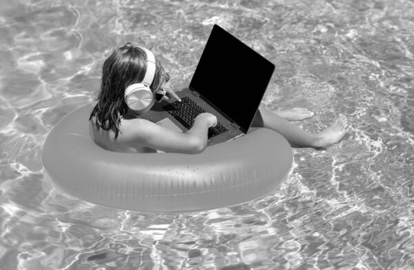 Funny little businessman freelancer relaxing in the pool, using laptop computer in summer water