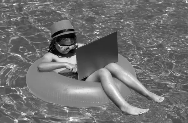 stock image Summer travelling. Little business man relaxing in the pool with laptop. Kid online working on laptop, swimming in a sunny turquoise water pool. Freelance work concept