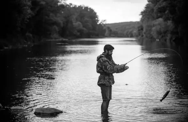 男人在湖边放松和钓鱼 渔民捕鱼设备 成功的接住快乐的留胡子渔夫在水里 拿着钓竿的人钓鱼的人 — 图库照片