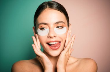 Siyah halkalar ve şişkinlik için göz bantları altında. Cildine bakıyorum. Göz bandı kullanan güzel bir kadın evde vakit geçiriyor. Günlük şımartma rutini. Modern kozmetik ürünleri. Göz bantları konsepti.