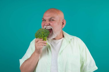 Son sınıf öğrencisi diyette brokoli yiyor. Yaşlı bir adam brokoli yiyor. Sağlıklı brokoli diyeti. Son sınıf öğrencisi stüdyoda brokoli tutuyor. Vegan Olgun Adam diyette. Yıllanmış diyet. Sağlıklı yemek.