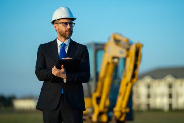 İnşaat işletmecisi ya da şantiye müdürü. İnşaat müdürünün portresi, kazıcının yanında şapka ve takım elbise giymiş. İnşaat yöneticisi veya denetçisi ile yenileme
