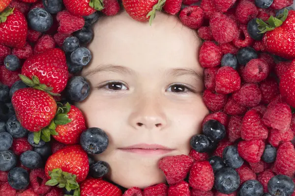 Funny fruits. Berries mix blueberry, raspberry, strawberry, blackberry. Child face with berry frame, close up