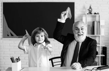 Kağıttan uçağı olan öğretmen ve okul çocuğu. Pedagog ve öğrenci eğleniyor. Etkin bir şekilde büyüyen ve gelişen ilgili öğrenciler. Okul öğrencileri boş vakitlerinde