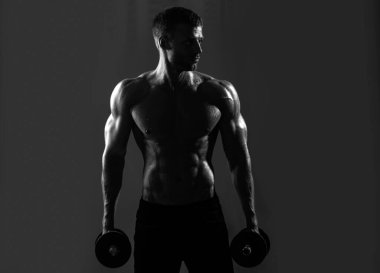 Sportif gövde, dambılı adam. Stüdyoda egzersiz yapan kaslı bir adam. Güçlü erkek, çıplak karın kasları.