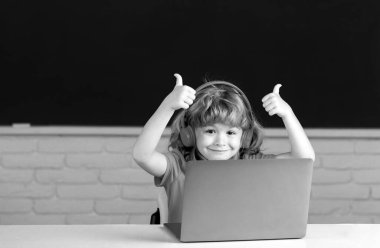 Zeki bir okul öğrencisi, güzel bir öğrenci dizüstü bilgisayara kulaklık takıyor, müzik dersi bilgisayarı kullanıyor. Video çağrısı, uzaktan öğretmenle e-çalışma. Okuldaki ilk günüm.