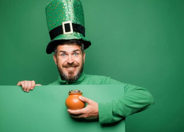 Green patricks background. Man in Patricks suit smiling. Man in Saint Patricks Day leprechaun party hat having fun on green background clipart