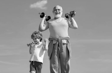 Büyükbaba ve oğlu egzersiz yapıyor. Aktif aile spor ve spor yapmayı sever. Baba ve oğul pazı ve kol kasları yapıyorlar. Rehabilitasyon merkezinde kıdemli adam antrenmanı