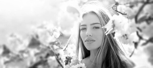 Outdoor fashion photo of beautiful young woman in flowers. Sensual girl on spring blossom background. Beauty romantic portrait of young pretty beautiful woman