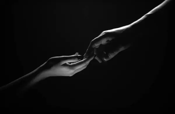 Two hands reaching toward. Tenderness, tendet touch hands in black background. Romantic touch with fingers, love. Hand creation of adam