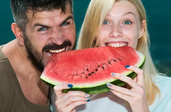 Happy carefree couple eat watermelon. Vitamins and healthy concept. Enjoying a watermelon. Couple friends eating a watermelon slice and laughing together. Holiday