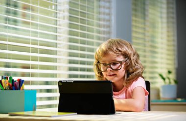 Okula dönelim. Çevrimiçi uzaktan öğrenme. Bilgisayarlı okul çocukları öğretmen ve sınıf grubuyla görüntülü konuşma yapıyorlar. Çocuk evden ders çalışıyor. Karantina ve koronavirüs sırasında evde eğitim