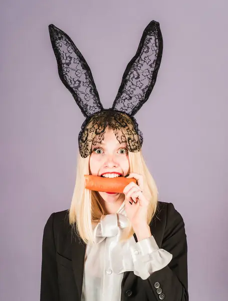 Surprised bunny woman wearing bunny ears and eat carrot. Happy easter and funny easter day. Smile easter