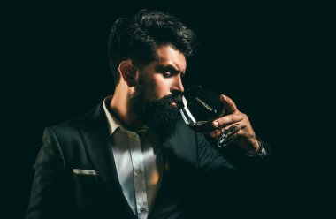 Neşeli sakallı adam pahalı konyak içiyor. Geleneksel viski içkisi, beyefendi içeceği. Klasik müziğin zarif ve şık adamı elinde konyakla bardak taşıyor.