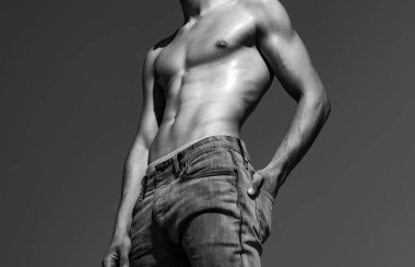 Mavi gökyüzünde seksi gövdesi olan kaslı genç adam.