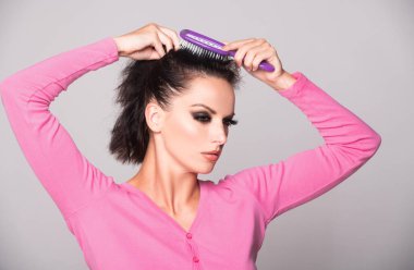 Saçını tarayan bir kadın. Saçlarını tarayan kadın modelin portresi. Saç fırçası, saç bakımı ve güzelliği olan kız