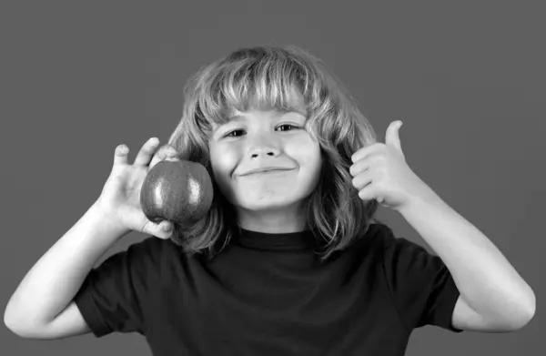 大拇指的小孩在吃苹果 可爱小男孩在蓝色背景下孤立无援的画像 — 图库照片