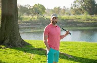 Golfçü golf sahasında golf sopası kullanıyor.