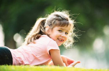 Mutlu kız bahar ya da yaz çimlerinde dinleniyor ve uzanıyor. Sevimli çocuk park çimlerinde yatıyor.