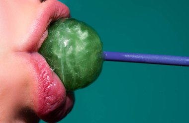 Şeker yalıyorum. Lolipop modeli. Kadın dudakları şeker emiyor. Kırmızı dudaklı çekici manken eşofman altı yiyor lolipop