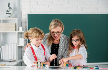 Schoolkids with teacher. Happy children from elementary school study at draw lesson. Teacher and little students portrait, teachers day.Pupils girl and boy with teacher painting at art school