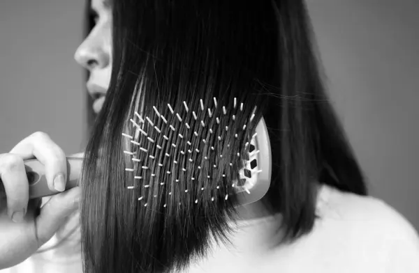Close up woman brushing hair with comb. Beautiful girl with long hair hairbrush