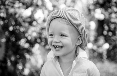 Açık havada gülümseyen sevimli çocuğun yakın portresi. Doğanın arka planında küçük bir çocuğun portresi, mutlu bir anaokulu çocuğu. Mutlu çocuk duyguları, gülen yüz