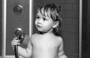 Tatlı erkek bebek banyoda banyo yapıyor ve banyo yapıyor. Duşun altında yıkanan çocuk. Komik çocukların yüzü yakın plan.