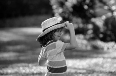 Yazlık doğa parkında saman şapkalı küçük sarışın bir çocuğun portresi. Komik yaz çocuğu suratı. Yaz tatili