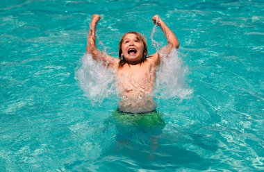 Havuzda su sıçratan heyecanlı çocuk. Havuzda yüzen küçük çocuk yaz tatilinde yüzer. Plaj denizi ve su eğlencesi