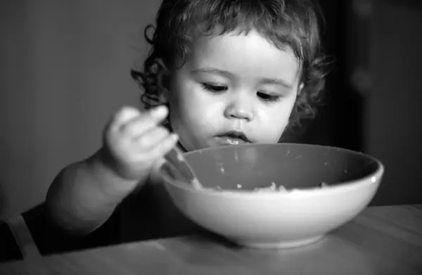 プレートから食べる面白い小さな赤ちゃんの男の子の肖像スプーンを閉じ保持 — ストック写真