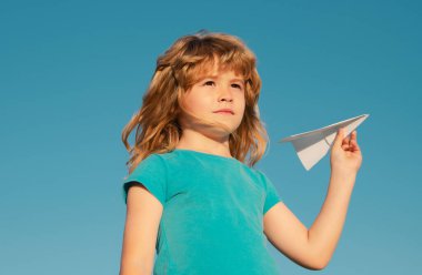 Güneşli bir günde kağıt uçakla oynayan bir çocuk. Çocuk rüyası, kağıt uçak, oyuncak uçak