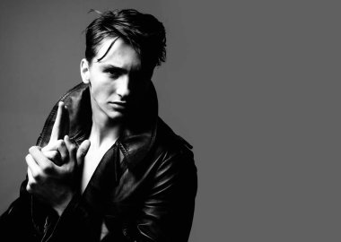 Gri arka planda izole edilmiş, parmak tabancası olan seksi bir adam.