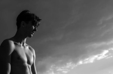 Kendine güveni olan adam gökyüzü arka planında metin ya da reklam için fotokopi alanı ile duruyor. Yakışıklı adam, moda tarzının portresi.