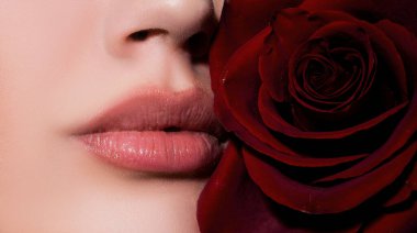 Close-up beautiful lips with red rose. Part of face, young woman close up plump lips with nude lipstick. Natural lip lipstick on lips