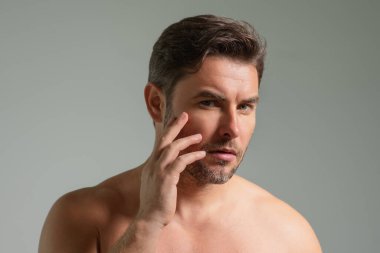 Orta yaşlı İspanyol adam tenine, cildine ve sakalına dokunuyor. Erkek güzellik ürünleri. Cilt bakımı, spa. Güzel bir adamın güzel portresi. Spa modeli, nemlendirici cilt kremi