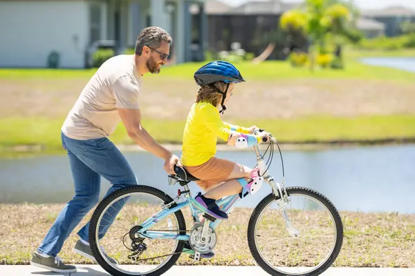 Happy Fathers day. Father and son in a helmet riding bike. Little cute adorable caucasian boy in safety helmet riding bike with father. Family outdoors summer activities. Childhood and fatherhood