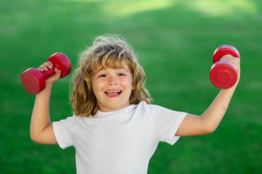 Spor çocuk antrenmanı. Çocuk halterle egzersiz yapıyor. Yaz sporu. Dambılı sportif çocuk. Formda çocuklar.