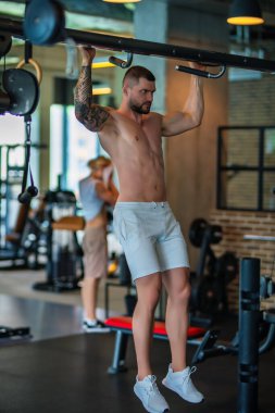 Sporcu kaslı adam spor salonunda çalışıyor. Dambılla egzersiz yapan atletik adam. Spor, spor konsepti, spor kulübü, fitness merkezi. Beden eğitiminde. Mükemmel kasları olan seksi bir vücut geliştirici.