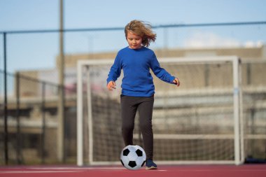 Çocuk futbolcu ya da futbol oyuncusu stadyumda gol için futbol topunu tekmeliyor. Spor anlayışı, rekabet. Çocuk futbol oynuyor. Futbol topu olan çocuk. Spor, çocuklar için futbol hobisi